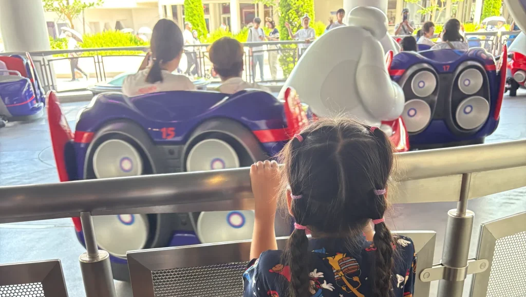 東京ディズニーランド「ベイマックスのハッピーライド」を、柵の前で見つめる子どもの後ろ姿